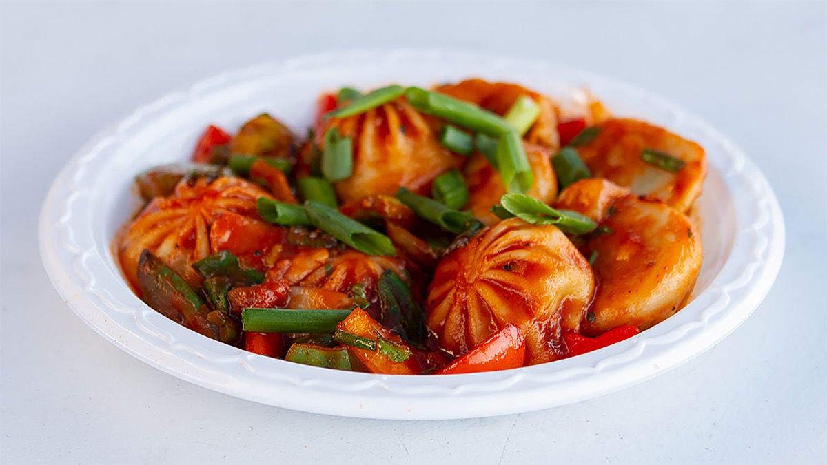 A plate of chili momos with red peppers and green onions